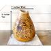 A handmade sunflower vase decorates an entryway table. It is 11 by 7 inches. The vase is made from a dried gourd. 